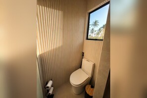 A compact bathroom with a toilet, a window, and a vertical blinds design.