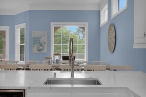 Una cocina con encimera de mármol, pileta de acero inoxidable y ventana con persianas.
