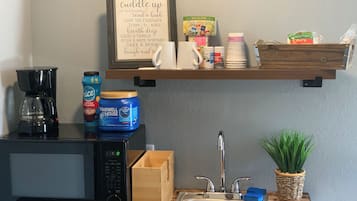 Una kitchenette con cafetera, microondas y un cartel enmarcado con consejos para relajarse.