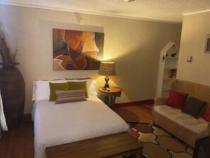 A hotel room with a bed, a lamp, a sofa, and a painting on the wall. - 3762 Bertrose Furnished Quaint Retreat (Fort Worth)