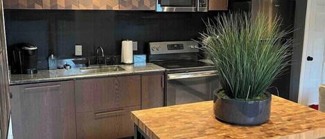 A modern kitchen with a central island, built-in appliances, and a potted plant.