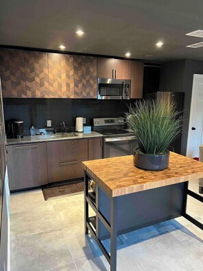 Una cocina moderna con una isla central, electrodomésticos integrados y una planta en maceta.