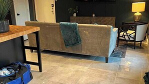 Una sala de estar moderna con un sofá, una mesa de centro, un televisor montado en la pared y una lámpara sobre una mesita auxiliar.