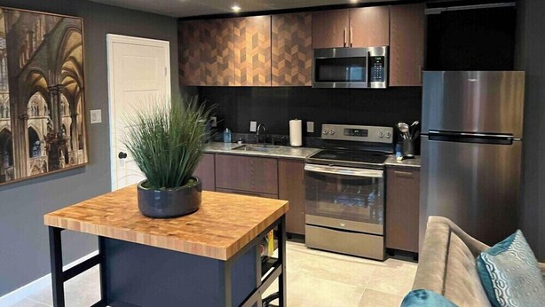 Una cocina moderna con electrodomésticos integrados, una isla de madera y un rincón comedor con sofá.