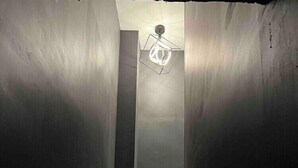 Una escalera con una lámpara en la parte superior que conduce a un espacio interior oscuro.