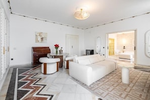Un salón moderno con un sofá blanco, una mesa de centro redonda y una araña.