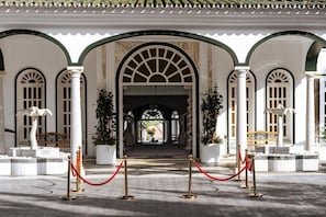 A grand entrance with a covered walkway, columns, and a statue.