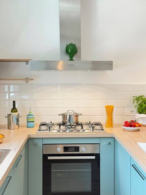 A modern kitchen with a gas stove, oven, and a stainless steel range hood. - La Camelia - Cozy house with a garden, air conditioning, Wi-Fi, and parking (Massa Lubrense)
