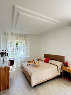 A bedroom with a bed, bedside table, and a window with curtains. - La Camelia - Cozy house with a garden, air conditioning, Wi-Fi, and parking (Massa Lubrense)
