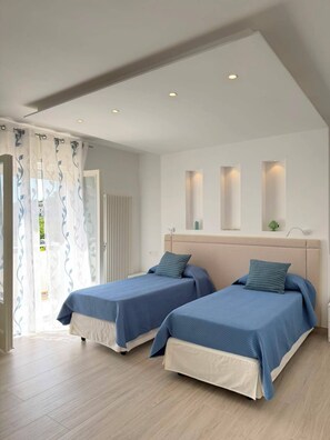 A bedroom with two beds, a white ceiling, and a view through a door. - La Camelia - Cozy house with a garden, air conditioning, Wi-Fi, and parking (Massa Lubrense)