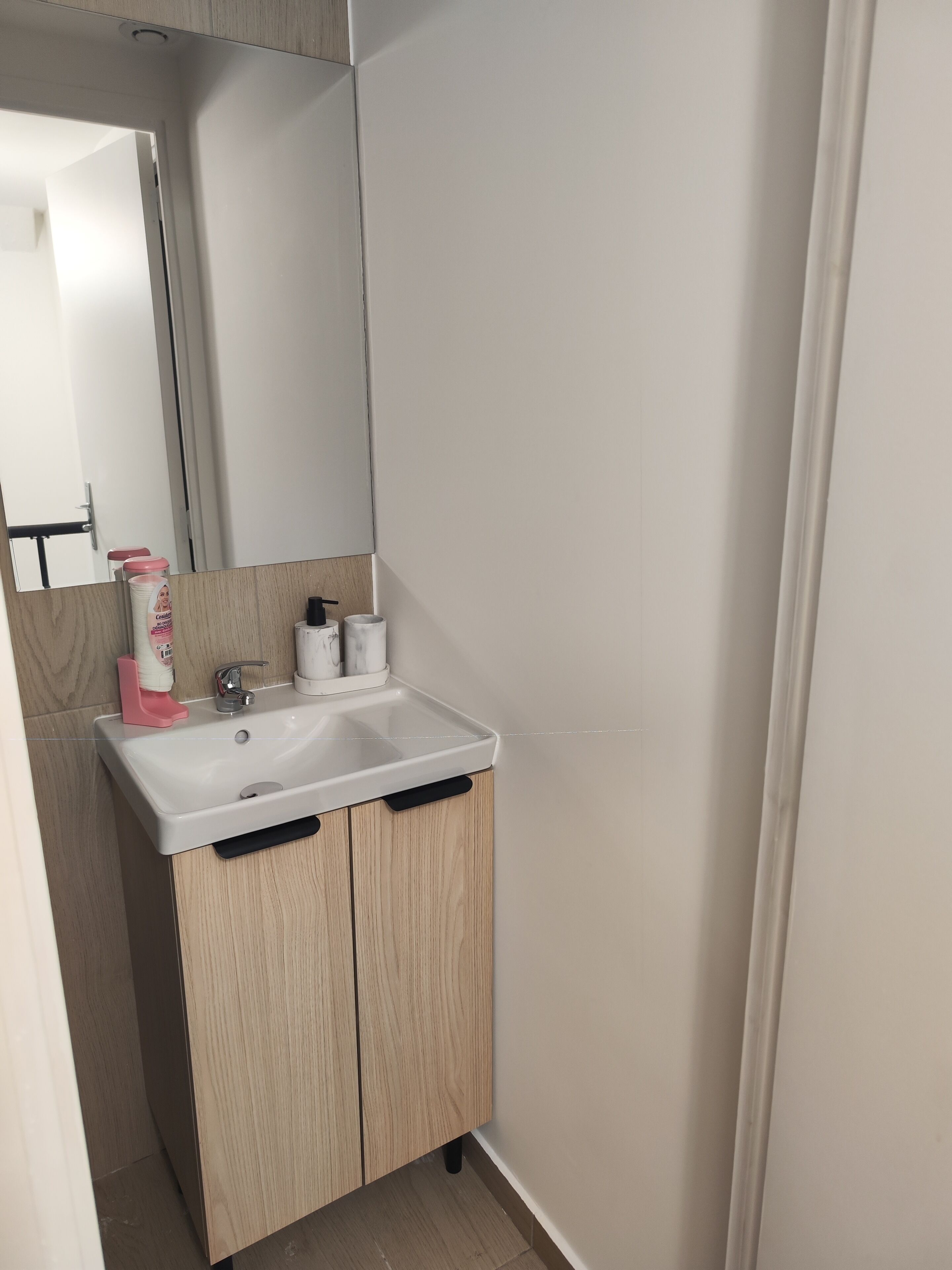 A bathroom with a white sink, wooden cabinets, a mirror, and a toilet.