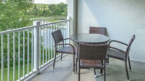 Een balkon met rieten meubilair en uitzicht op een meer.
