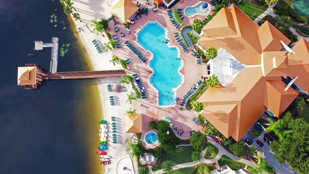 Luchtbeeld van een resort met een groot zwembad, een strandgedeelte en een steiger.