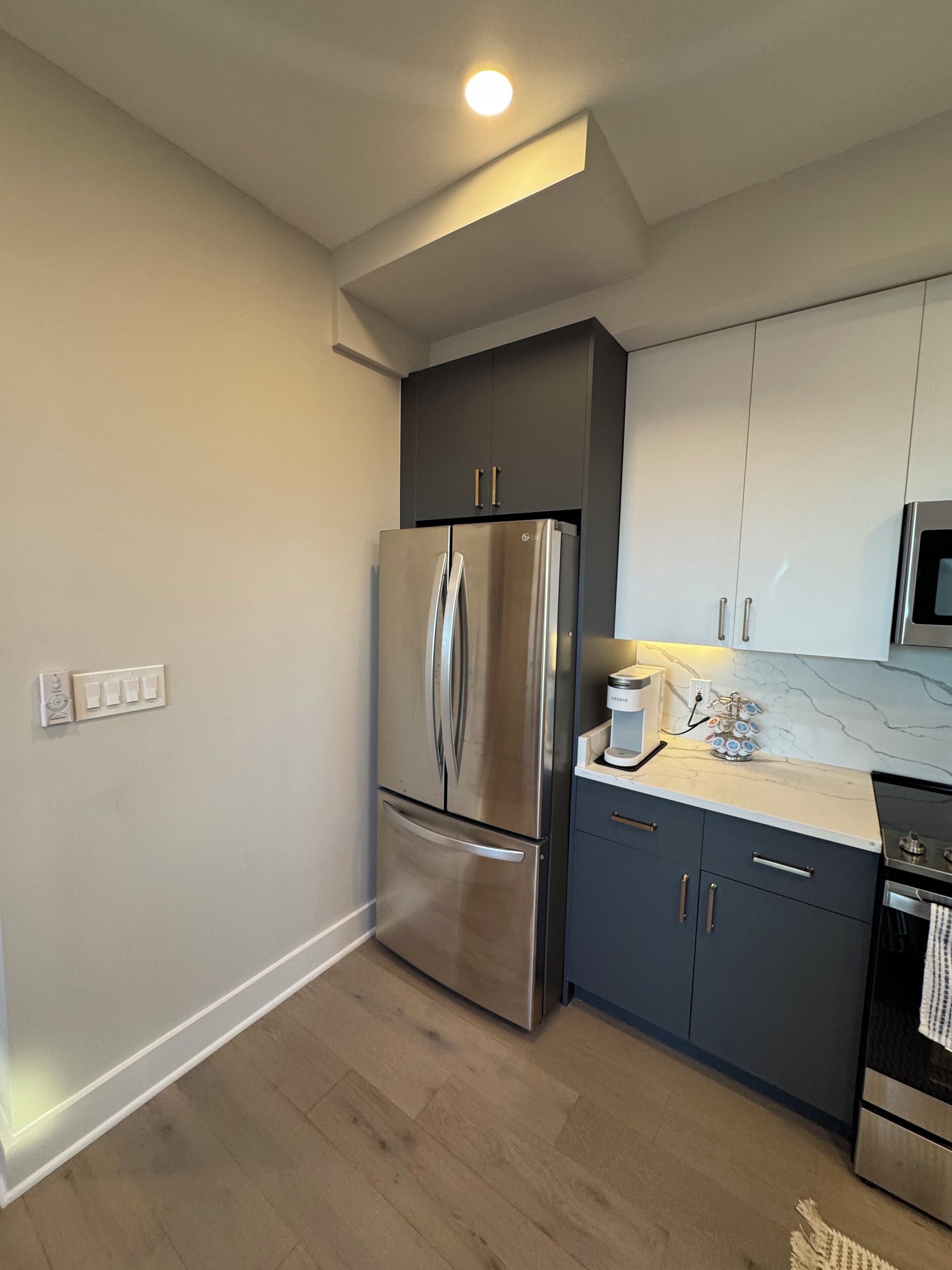 A modern kitchen with stainless steel appliances, a marble countertop, and a built-in oven.
