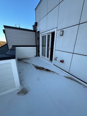 A building with a flat roof, a sliding glass door, and a small outdoor area with a concrete floor. - Modern penthouse condo with private rooftop terrace, views of DC Nat’l Arboretum (Washington)