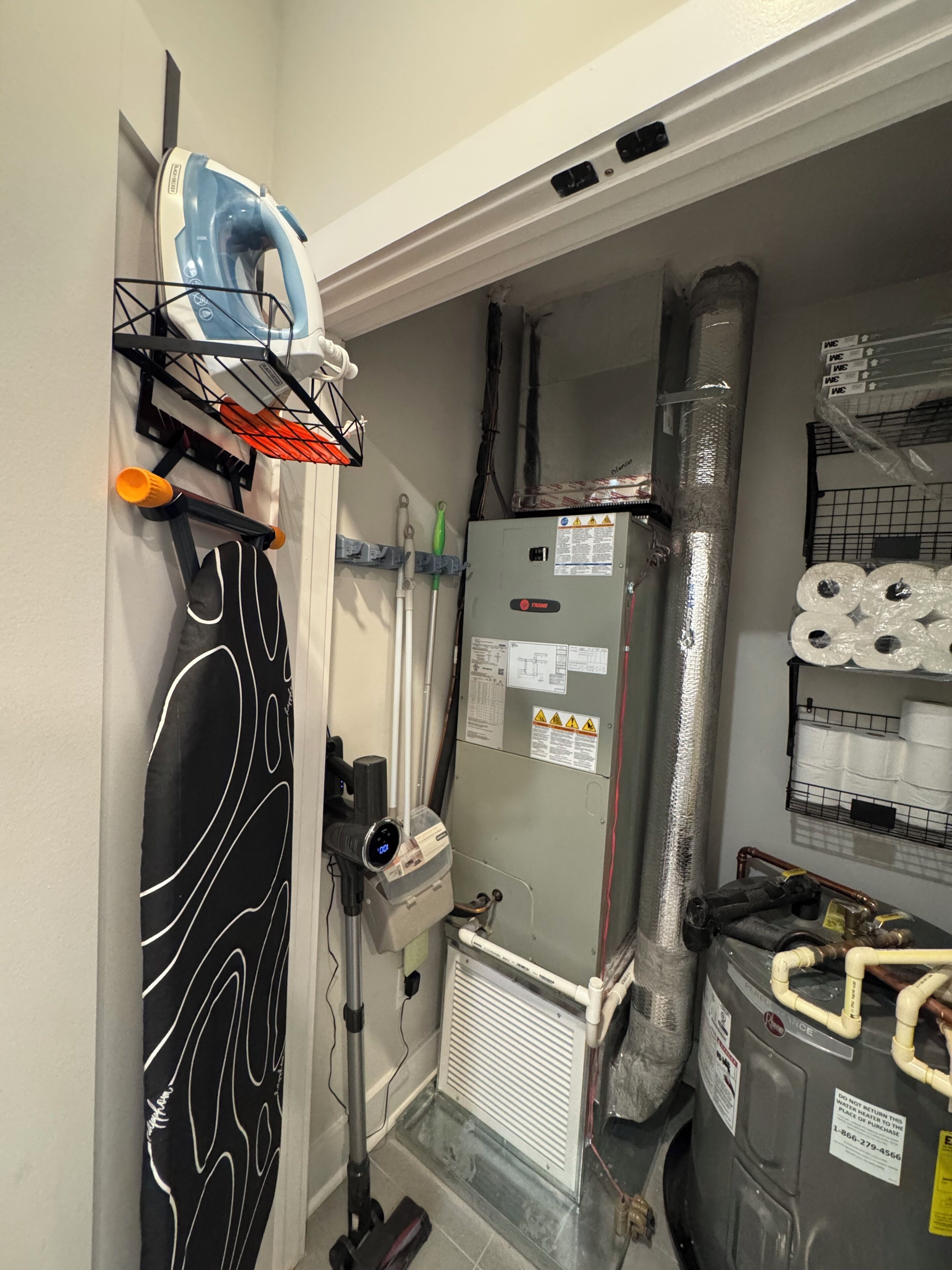 A utility room with an iron, a water heater, and a toilet paper dispenser.