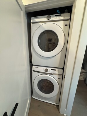 A stacked washer and dryer unit in a corner of a room. - Modern penthouse condo with private rooftop terrace, views of DC Nat’l Arboretum (Washington)