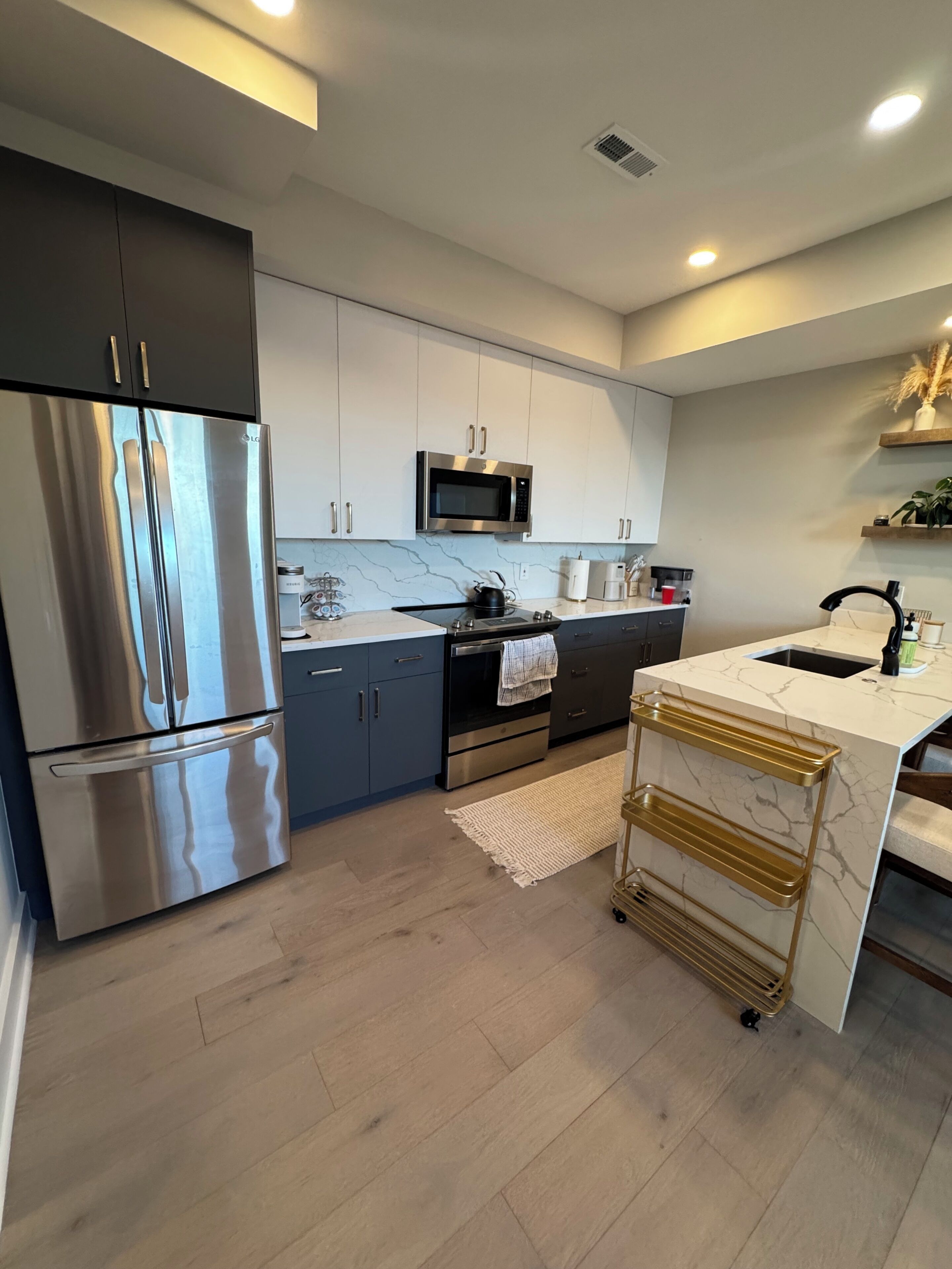 A modern kitchen with stainless steel appliances, marble countertops, and a built-in oven.