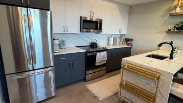 A modern kitchen with stainless steel appliances, marble countertops, and a built-in oven.