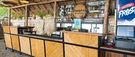 A bar area with a wooden counter, a computer, and a sign for 'Paradiso Nicaragua'.