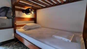 A single bed with a headboard, a bedside lamp, and a folded towel on the bed.