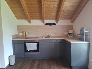 Eine kleine Küche mit Backofen, Spüle und Kaffeemaschine.