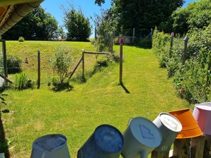 Ein eingezäunter Garten mit einer Holzschaukel, einem kleinen Baum und einem Metalltor.