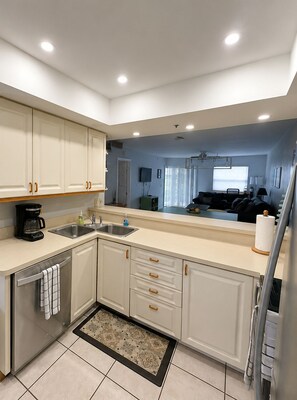 A modern kitchen with white cabinetry, a stainless steel sink, and a coffee maker.