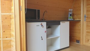 Eine kleine Küchenzeile mit Mikrowelle, Kaffeemaschine und Kühlschrank.