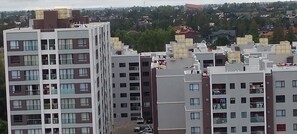 Ein mehrstöckiges Wohngebäude mit Balkonen, einem Parkplatz und Blick auf eine Wohngegend mit Häusern und Bäumen.