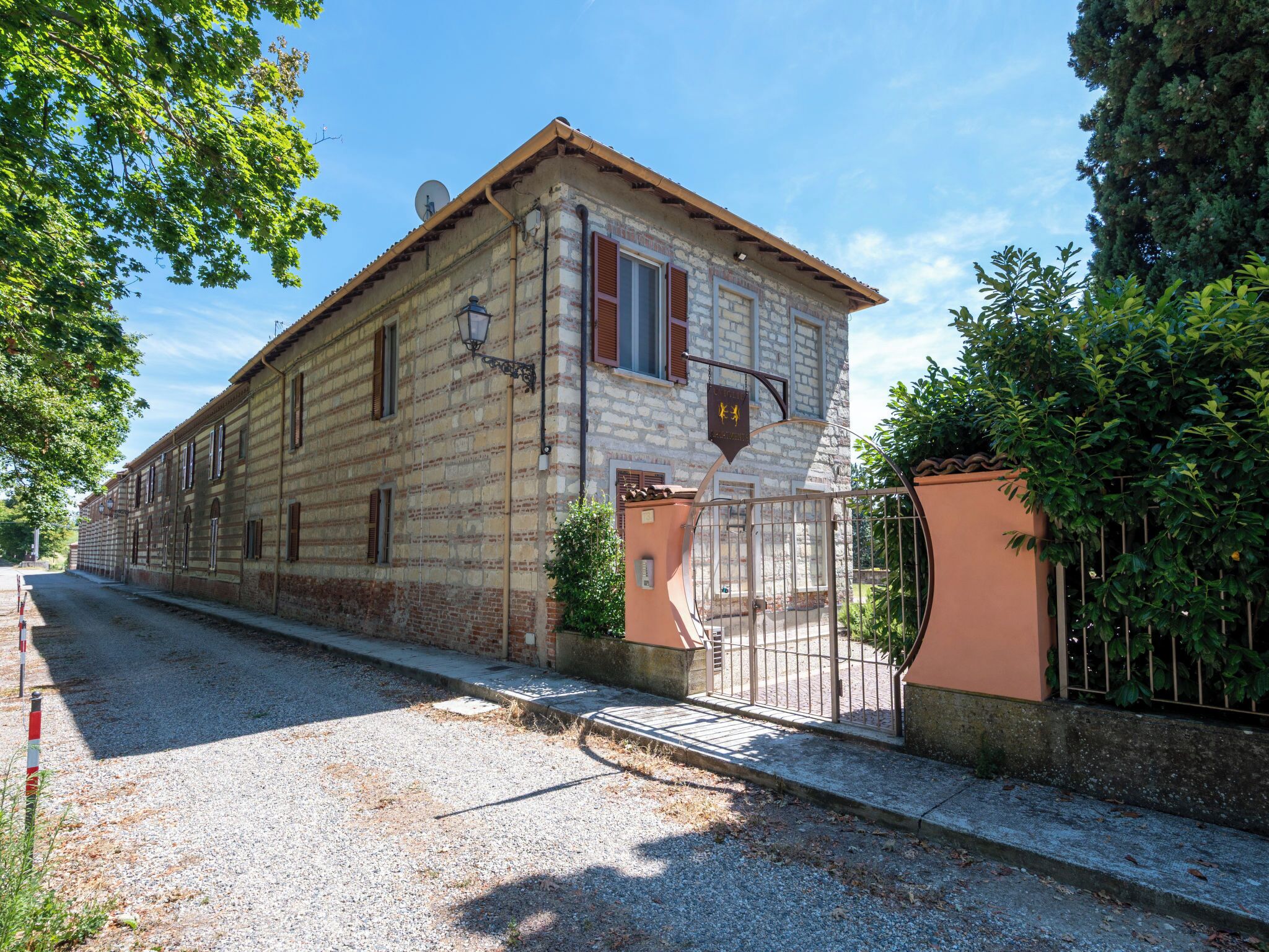 A two-story stone building with a traditional facade, a gated entrance, and a gravel driveway.