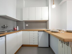 A modern kitchen with white cabinets, a wooden countertop, a dishwasher, and a small refrigerator. - Lunariae by Interhome (Rosignano Monferrato)