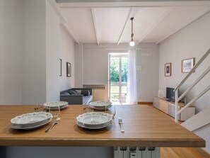 Ein Essbereich mit einem Holztisch, gedeckt für vier Personen, einer Couch und einer Treppe.