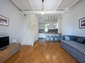 Eine moderne Wohnung mit Holzboden, einer Treppe, einer Küche und einem Wohnbereich mit Sofa und Fernseher.