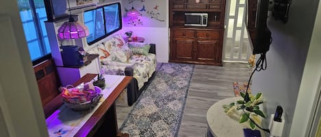 A cozy living space with a sofa, a coffee table, a microwave, and a patterned rug.