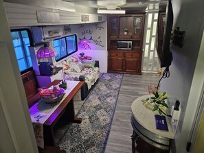 A cozy living space with a sofa, a coffee table, a microwave, and a patterned rug. - Super Cozy Rv with all the upgrades to feelhome. (Summerfield)