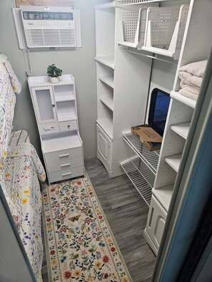A compact storage room with shelves, a small plant, and a box on a shelf. - Super Cozy Rv with all the upgrades to feelhome. (Summerfield)