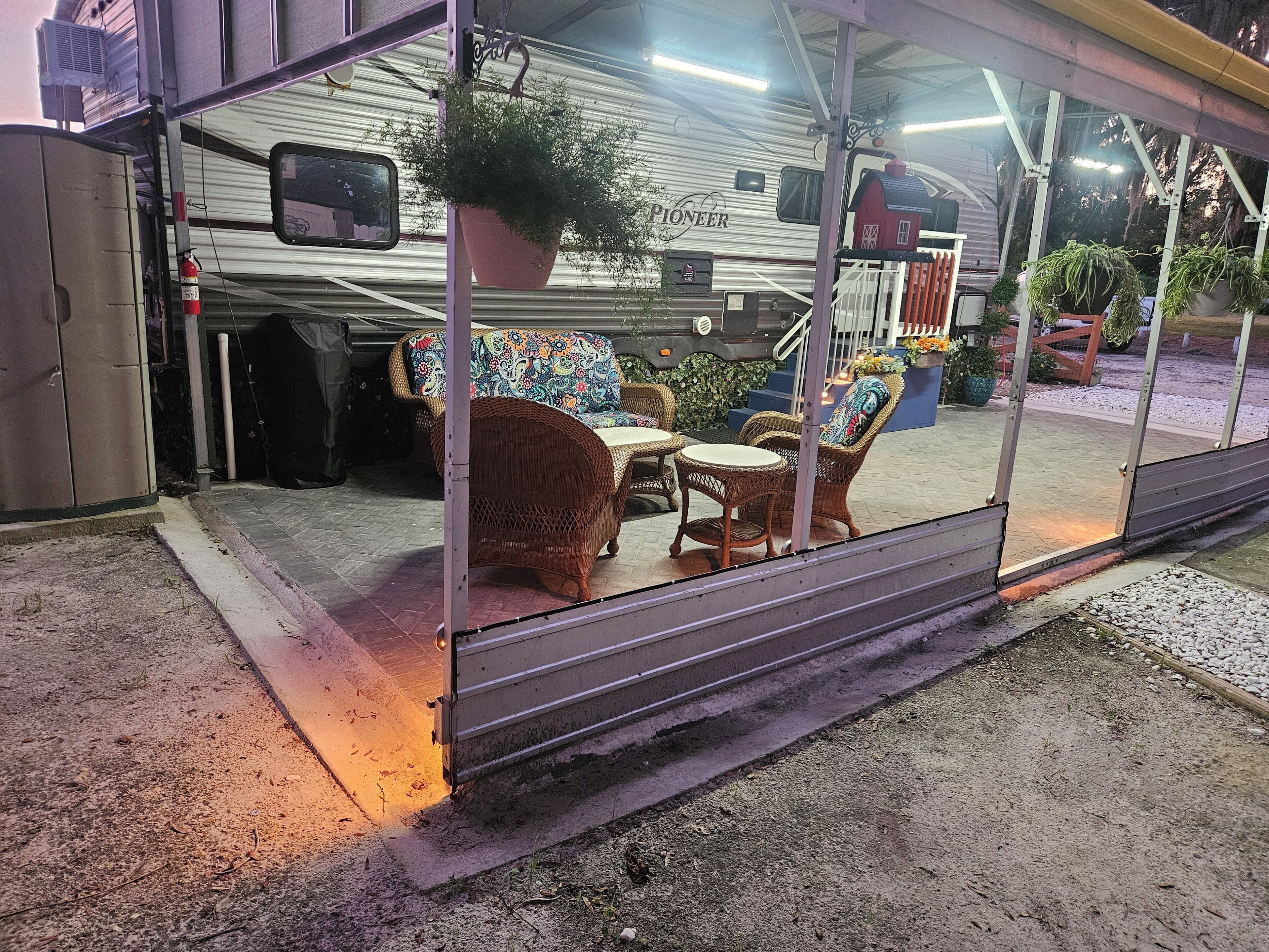 Un espace extérieur aménagé, abrité et doté de meubles en osier et d’une plante en pot.