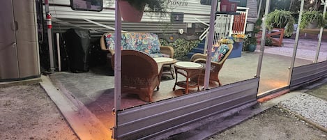 Un espace extérieur aménagé, abrité et doté de meubles en osier et d’une plante en pot.