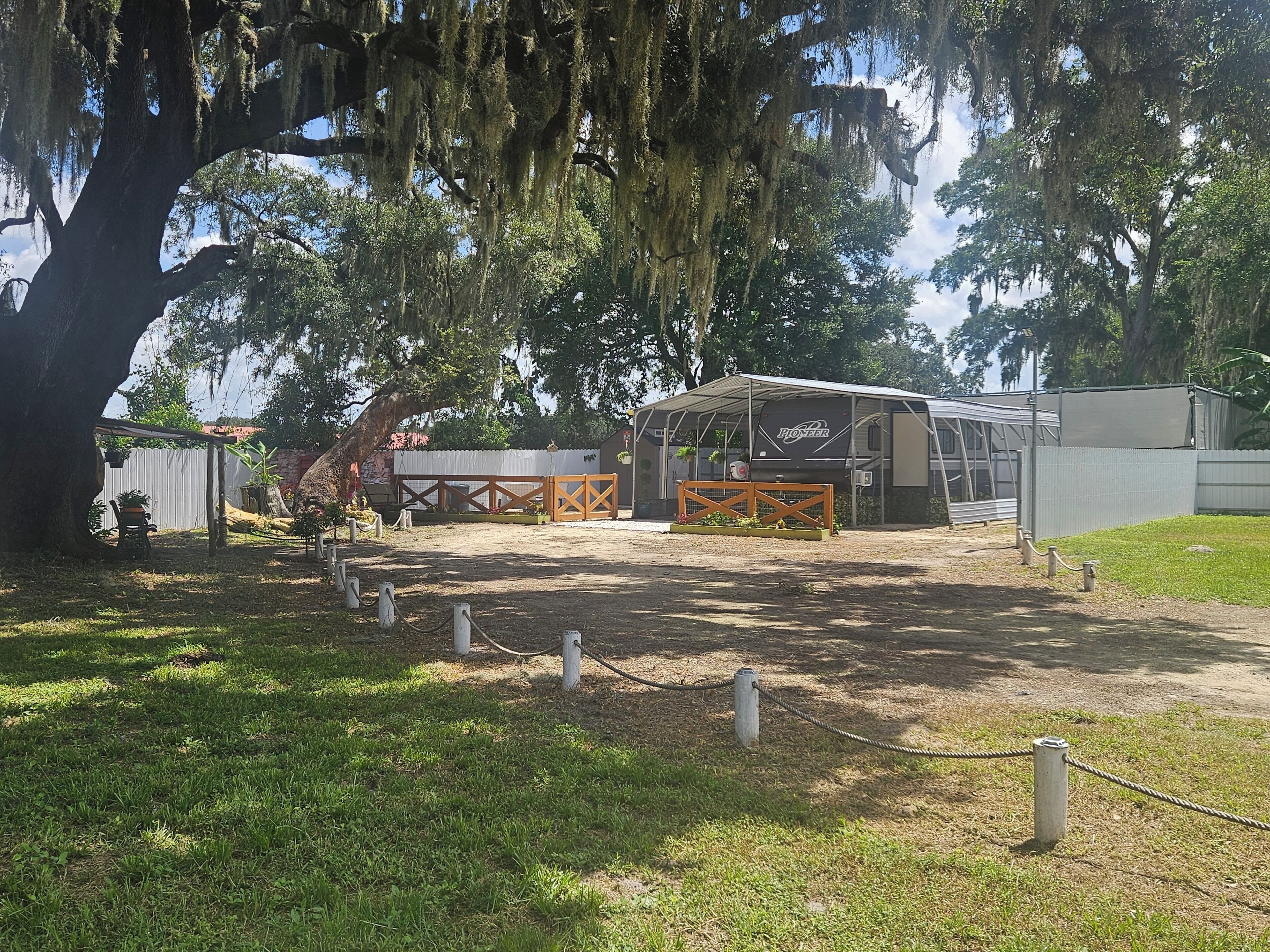 A covered outdoor area with a fenced entrance, a large tree with hanging moss, and a building labeled 'Pioneer.'