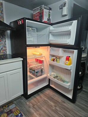 A corner refrigerator with multiple shelves and compartments, including a freezer section at the bottom.