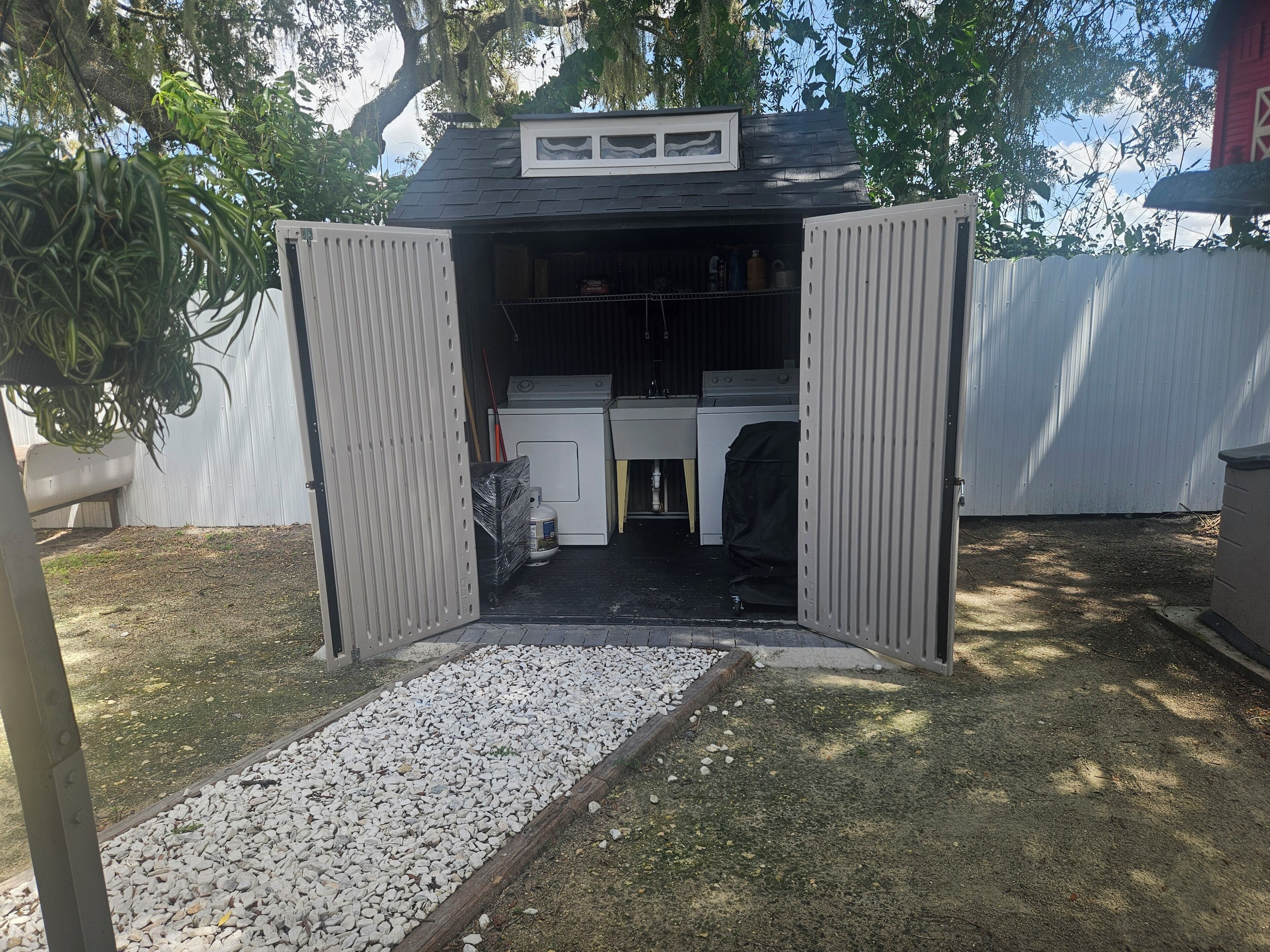A garage with a workbench, a washing machine, and a covered vehicle.