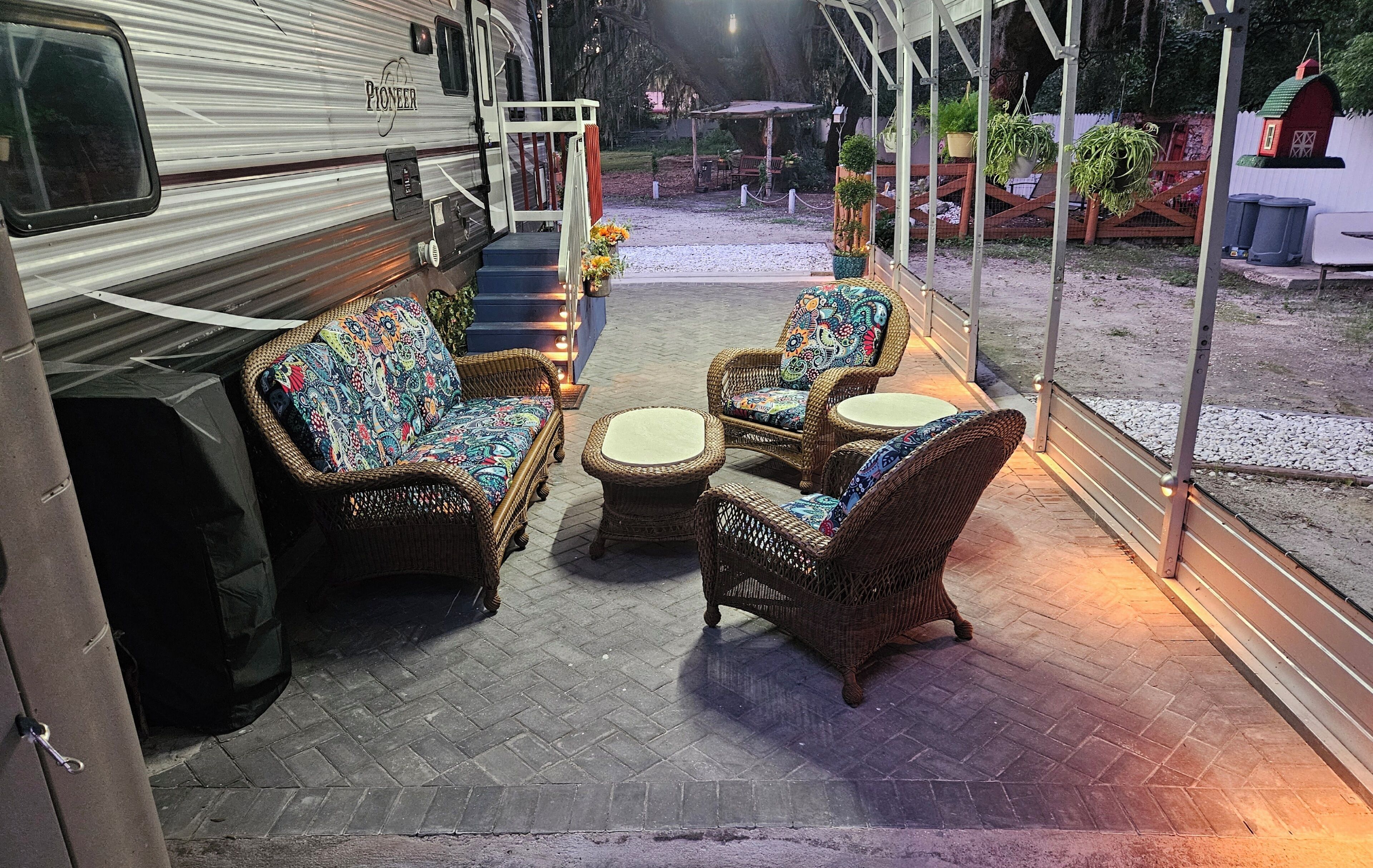 A Pioneer RV with a covered patio area featuring wicker furniture and a small table.