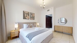 Ett hotellrum med en säng, sänglampor, ett element, en spegel och konstverk på väggen.