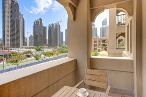 A balcony with a table and a cup, overlooking a cityscape with high-rise buildings and construction cranes. - Arabian Style 1 Bed l Near to Dubai Mall (Downtown)