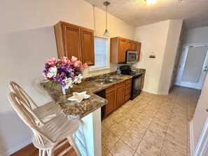 A kitchen with granite countertops, wooden cabinets, a stainless steel sink, a microwave, and a stove.