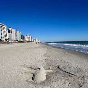 Una playa con una hilera de edificios de varios pisos al fondo.