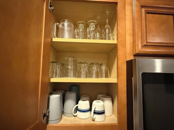Ein Küchenschrank mit Regalen voller verschiedener Gläser und Tassen.