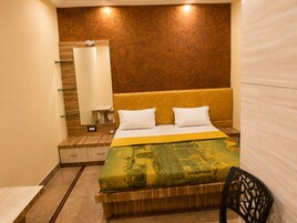A hotel room with a bed, a nightstand, a mirror, and a chair.