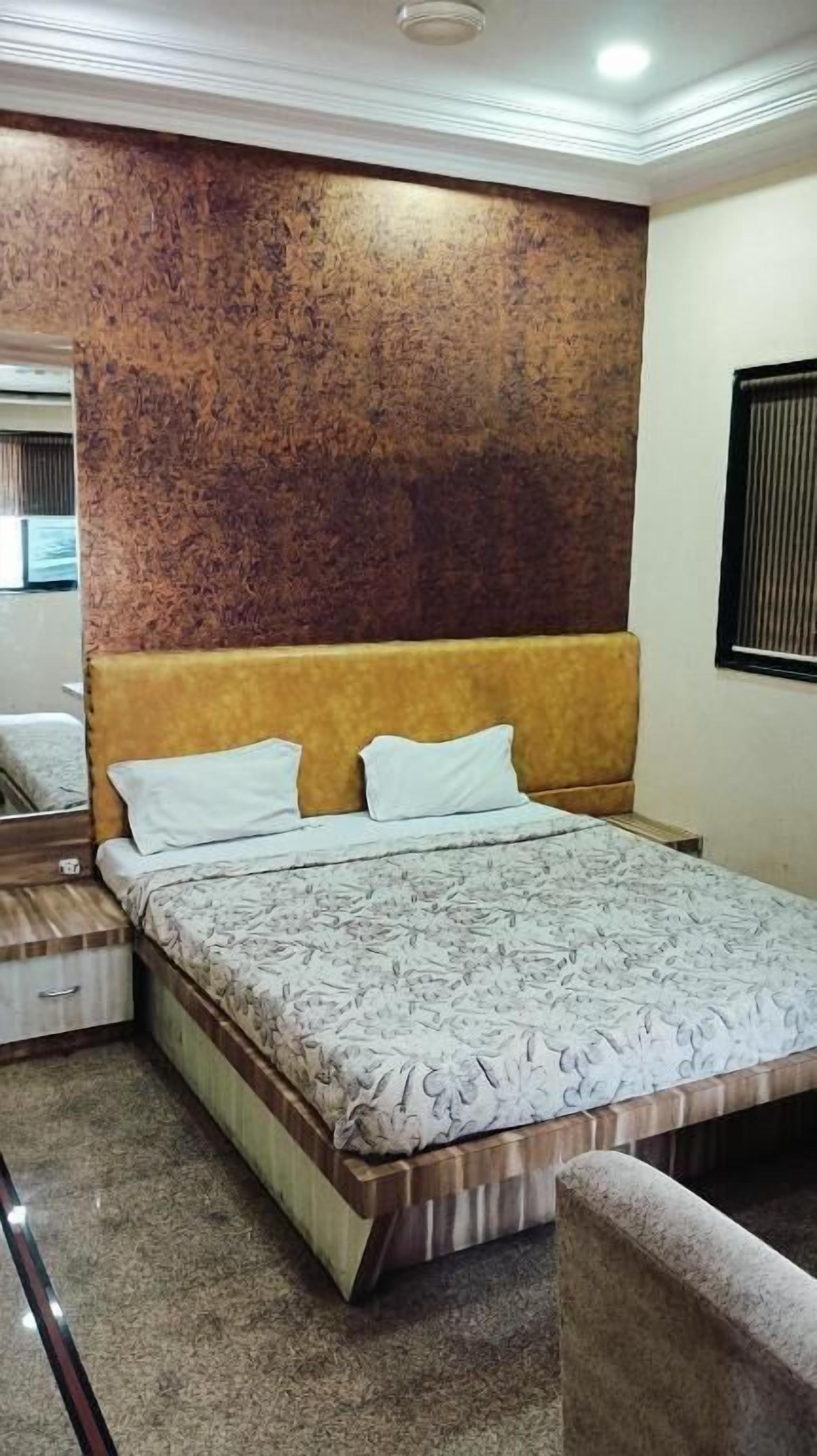 A bedroom with a bed, a headboard, a mirror, and a window.